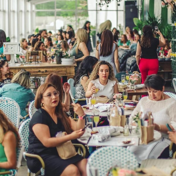Women gather at Greenhouse Kitchen + Bar, enjoying drinks and conversation in a bright, airy space.