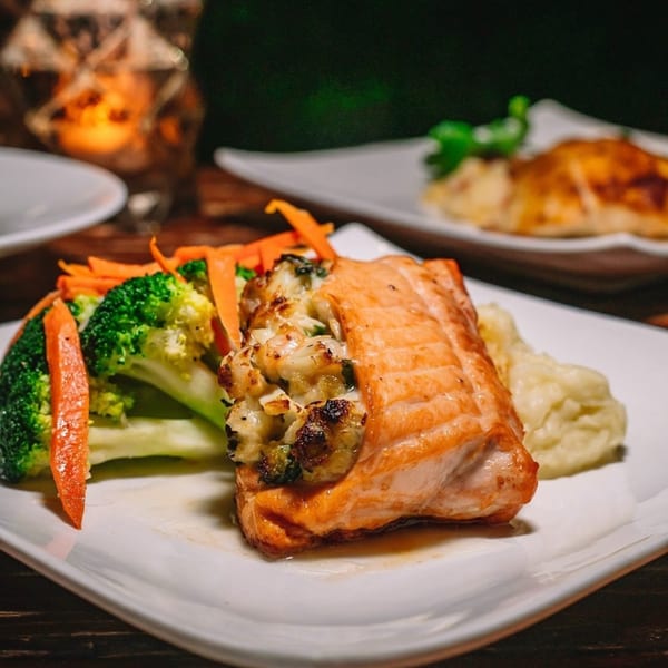 Stuffed salmon with broccoli, carrots, and mashed potatoes on a white plate at Greenhouse Kitchen + Bar.